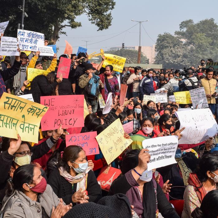 Large group of people protesting outdoors with colorful signs, demanding policy changes.