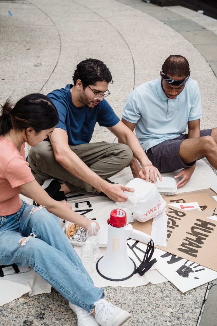 Group of young adults taking a break at a protest with signs and a megaphone.